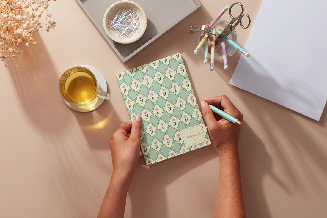 A woman holding a green notebook with subtle gold foil detail