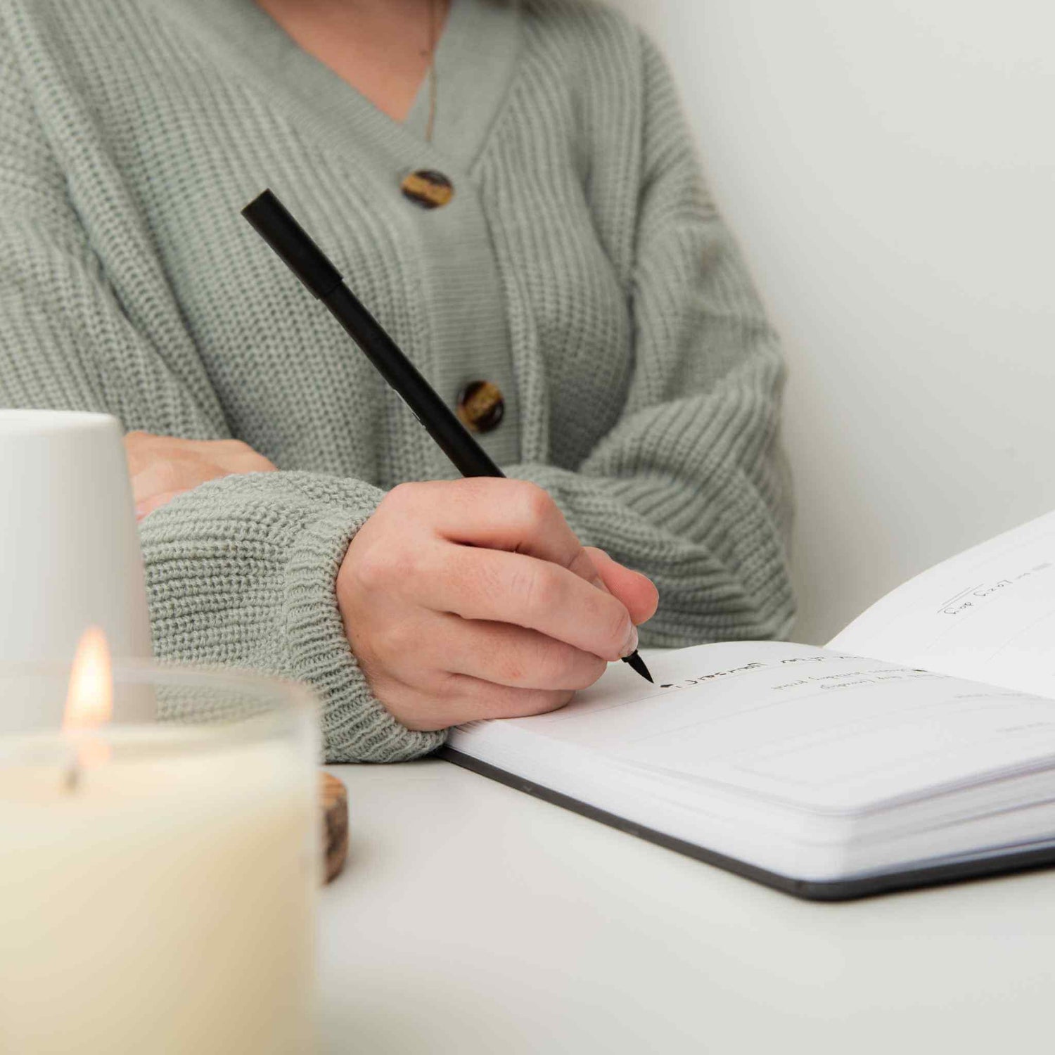 Image of woman writing in a journal with lit candle