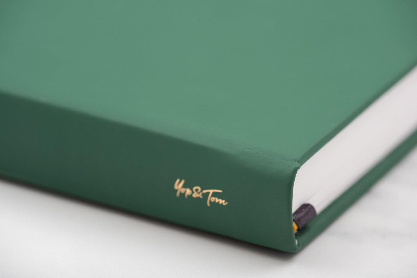 Close up of Yop & Tom logo on spine of power of 3 goal planner in forest green